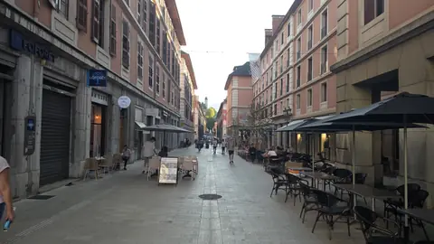The café street, tables out, a tower at the far end of it.